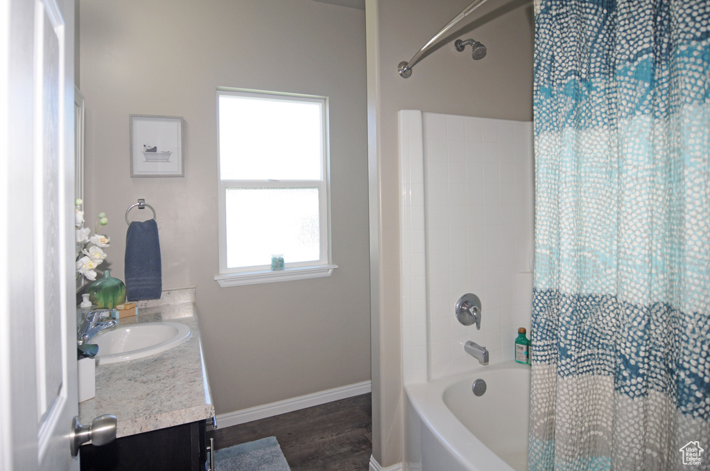 Bathroom with shower / bath combination with curtain, hardwood / wood-style floors, and vanity