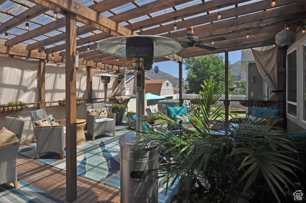 Wooden deck with ceiling fan, an outdoor living space, and a pergola