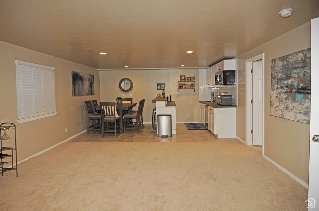 Kitchen featuring white cabinets, light carpet, and tasteful backsplash