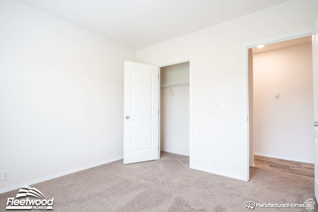 Unfurnished bedroom with a closet and light carpet