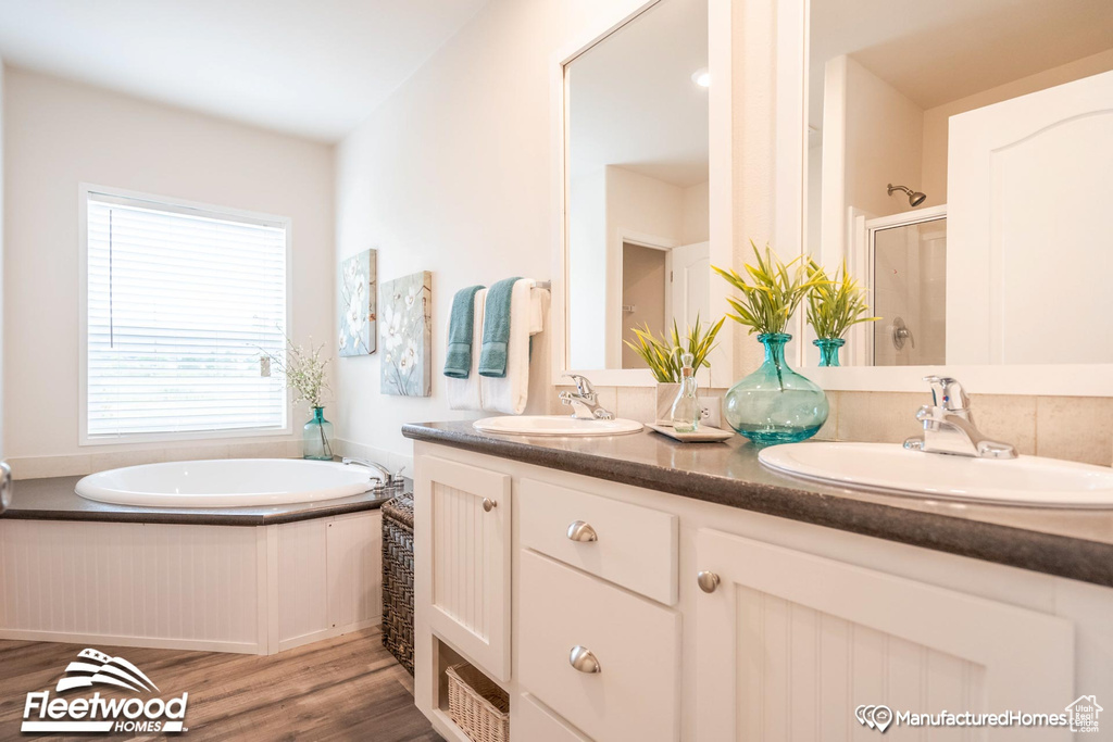 Bathroom with hardwood / wood-style flooring, shower with separate bathtub, and double sink vanity