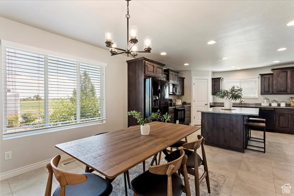 Tiled dining space featuring sink and an inviting chandelier