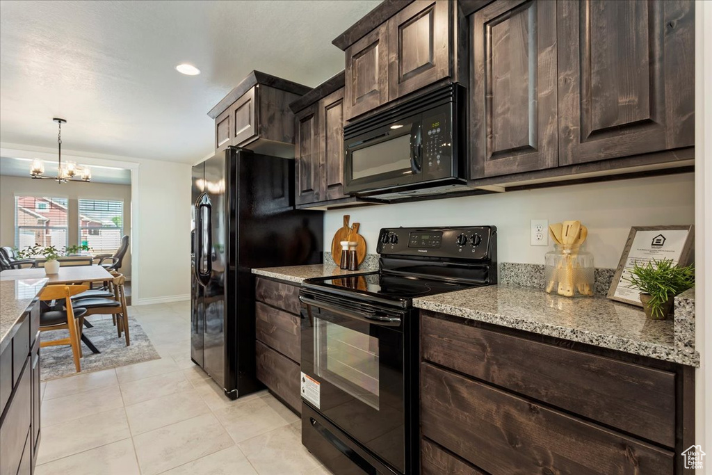 Kitchen with black appliances, light tile patterned floors, light stone countertops, and dark brown cabinets