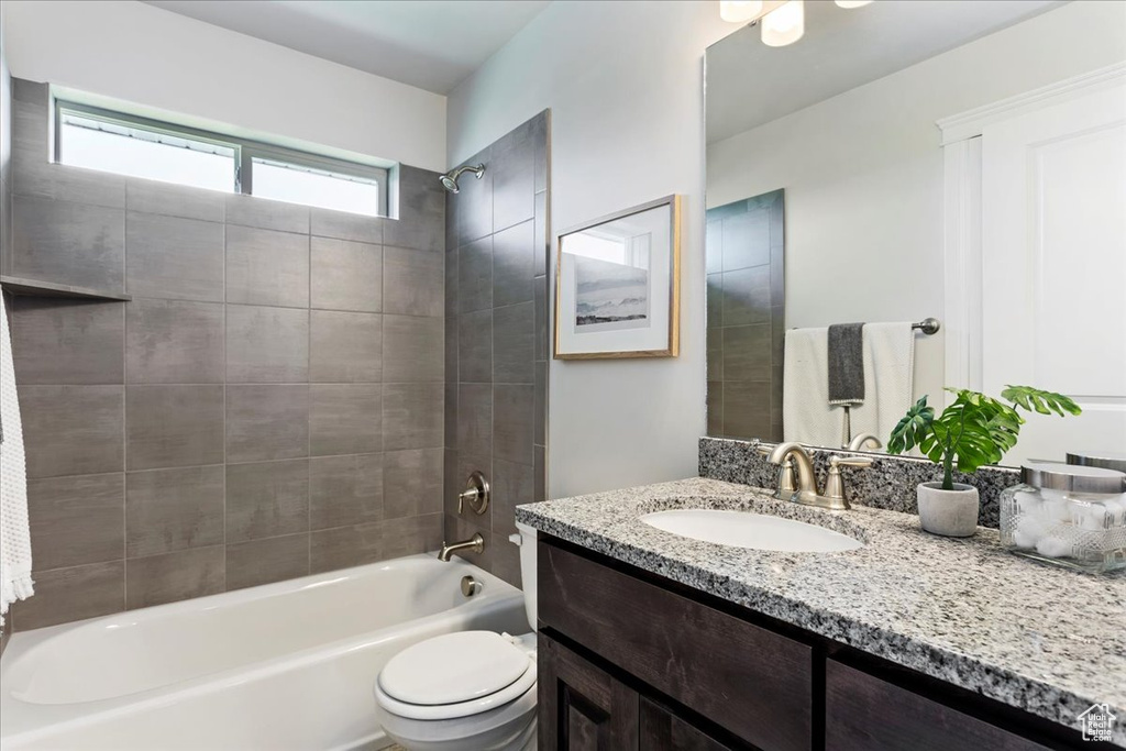 Full bathroom with toilet, tiled shower / bath, and vanity