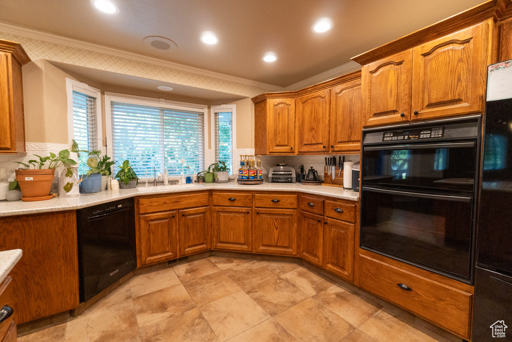 Kitchen featuring backsplash, light tile patterned floors, sink, black appliances, and crown molding