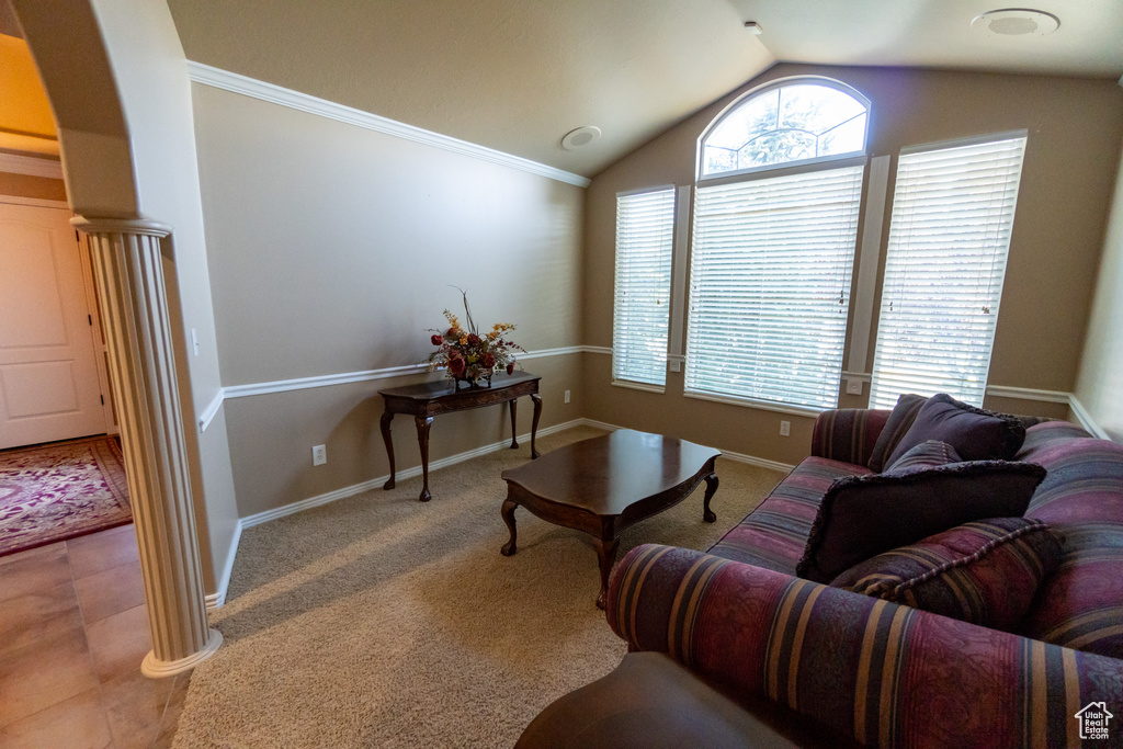 Living room featuring decorative columns, tile patterned flooring, and lofted ceiling