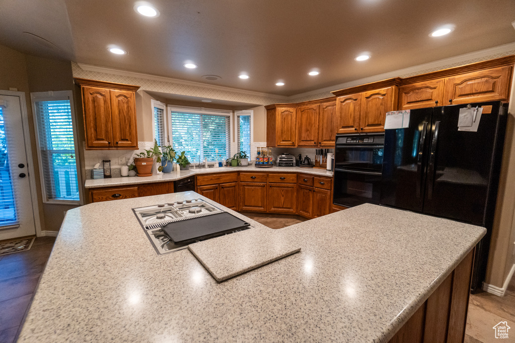 Kitchen featuring sink, black appliances, and tasteful backsplash