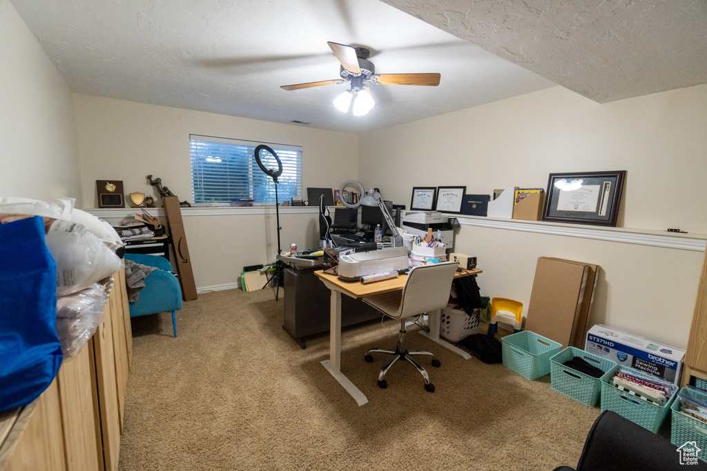 Carpeted office featuring a textured ceiling and ceiling fan