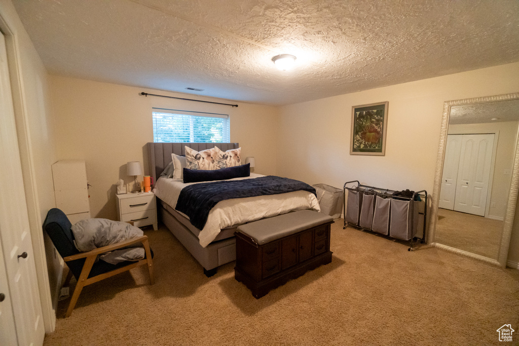 Bedroom featuring a textured ceiling and light colored carpet