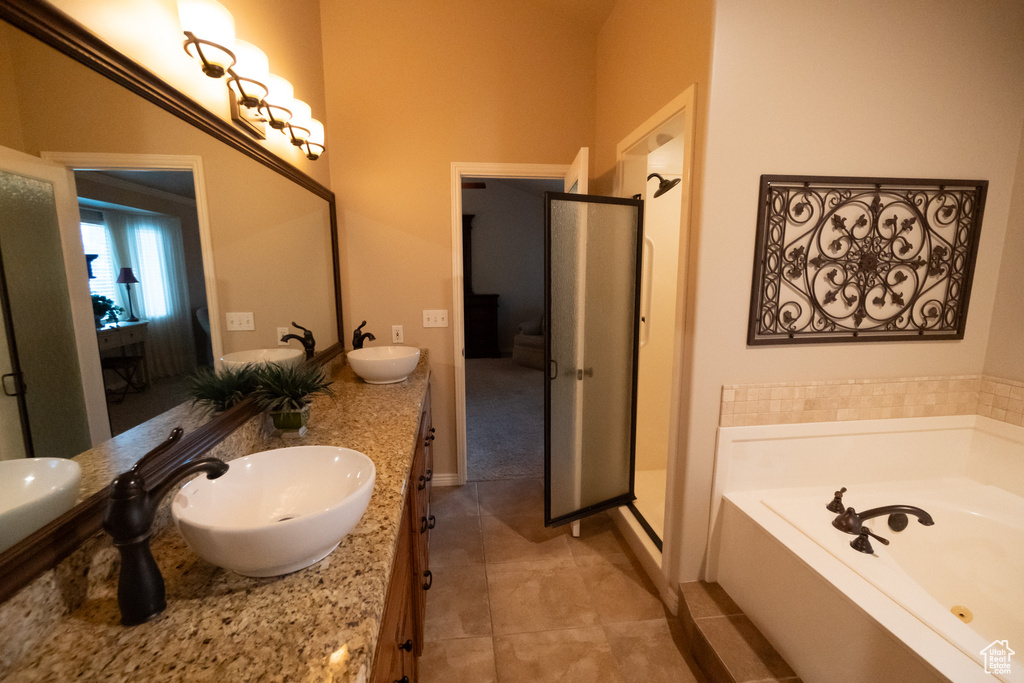 Bathroom featuring plus walk in shower, dual bowl vanity, and tile patterned floors