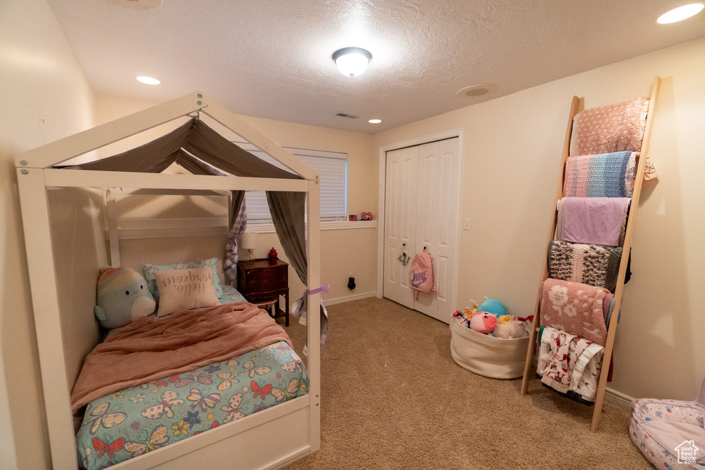 Bedroom featuring carpet, a closet, and a textured ceiling