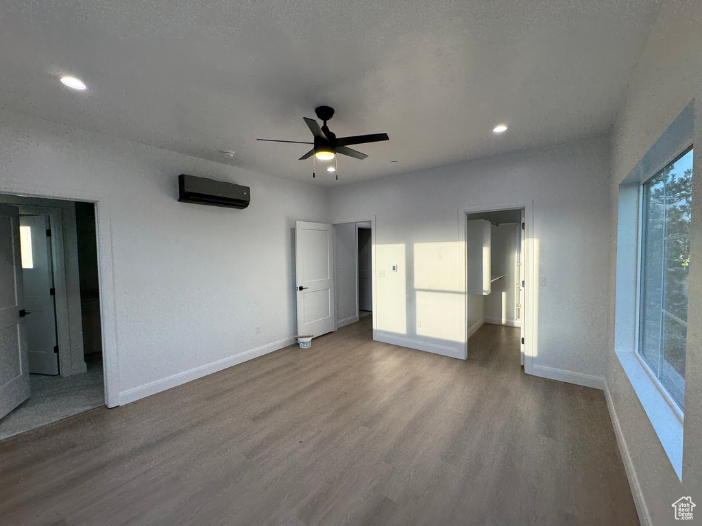 Unfurnished bedroom featuring baseboards, recessed lighting, a wall mounted AC, and wood finished floors