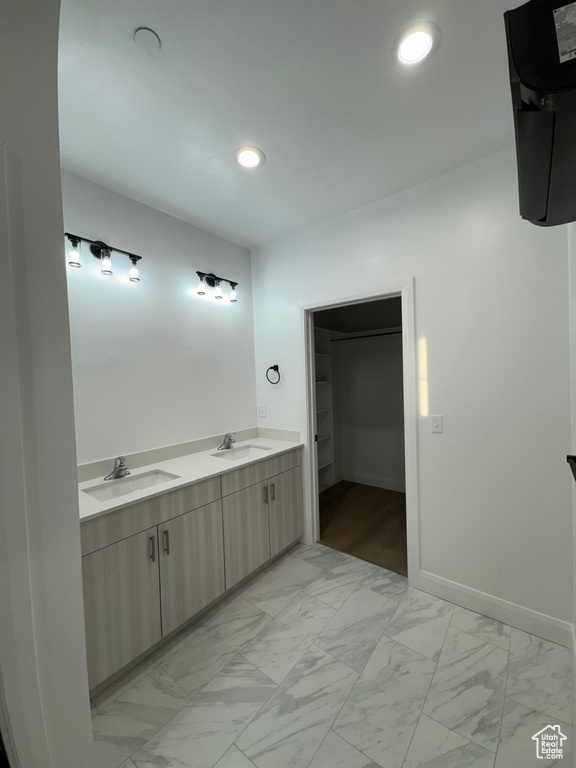 Full bath with a sink, a spacious closet, baseboards, and marble finish floor