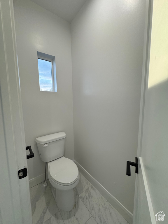 Bathroom with toilet, marble finish floor, and baseboards