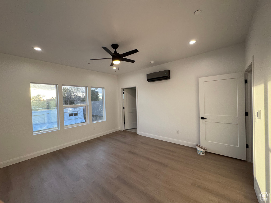Unfurnished bedroom featuring a wall mounted air conditioner, baseboards, recessed lighting, and wood finished floors