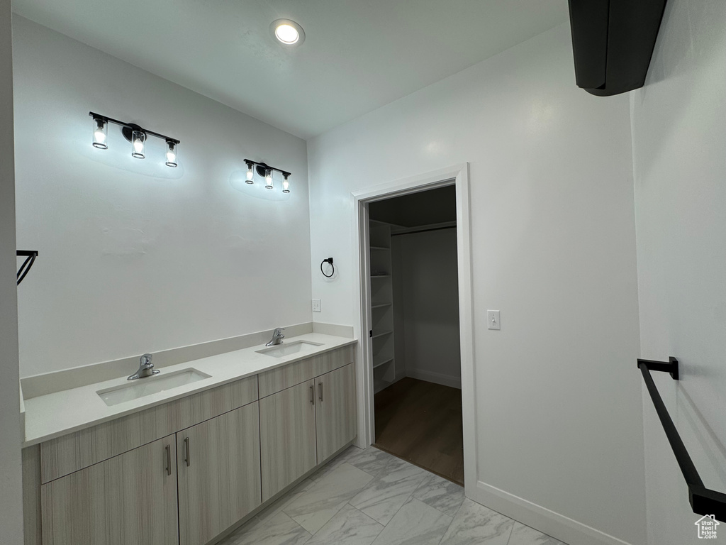 Bathroom with a sink, a walk in closet, baseboards, and marble finish floor