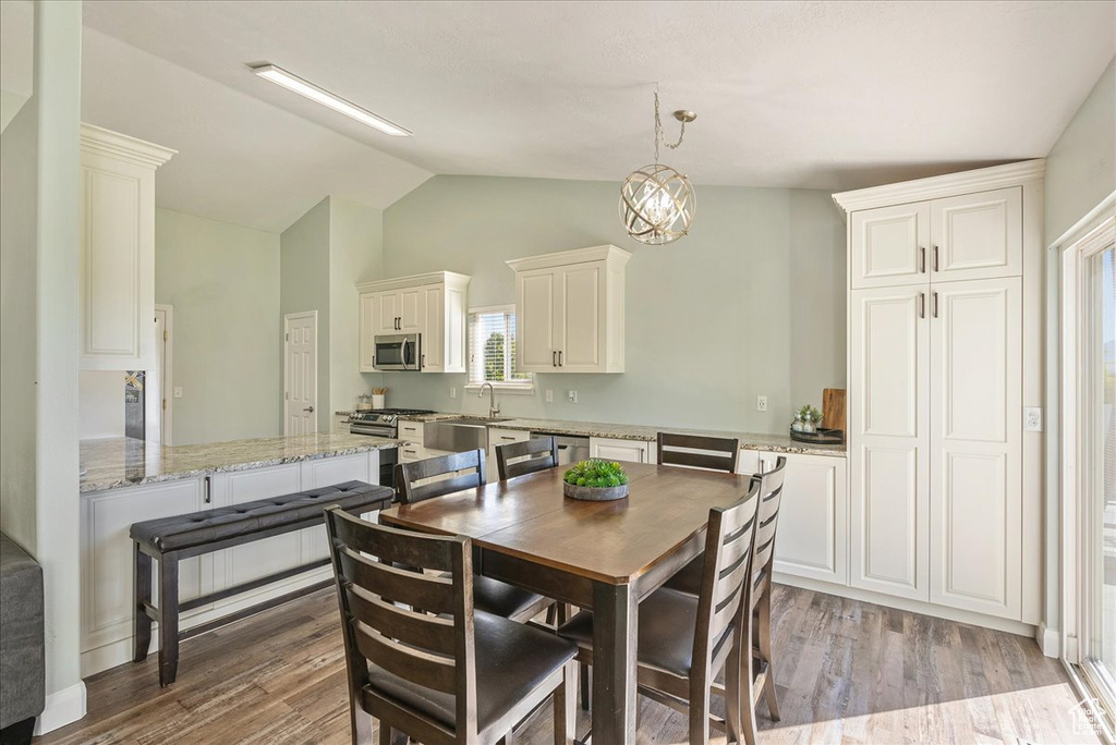 Dining room featuring hardwood / wood-style floors, sink, and lofted ceiling