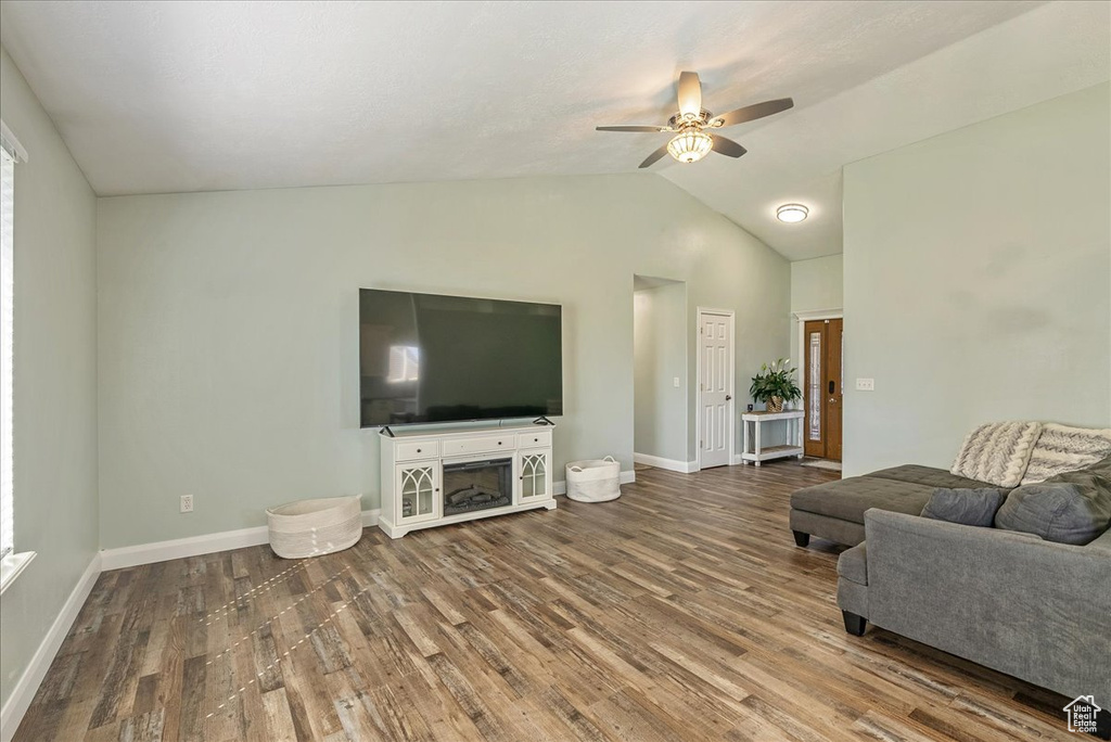 Living room featuring hardwood / wood-style floors, vaulted ceiling, and ceiling fan