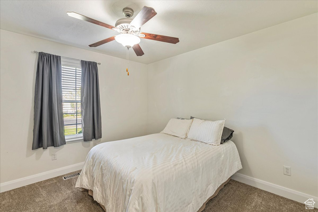 Carpeted bedroom featuring ceiling fan