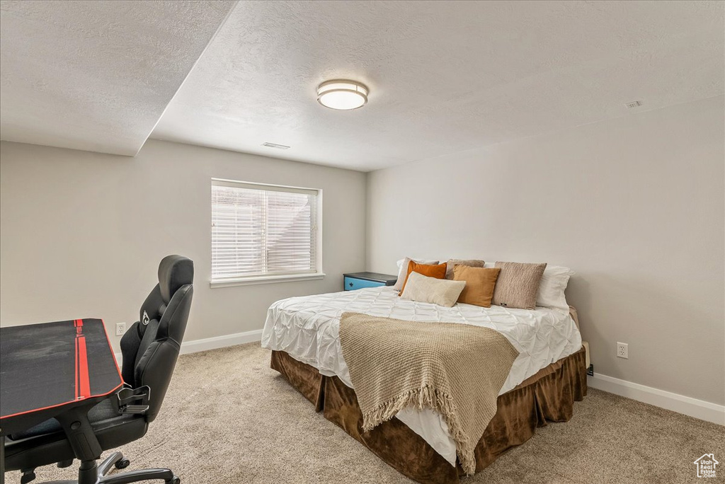 Bedroom with light colored carpet and a textured ceiling