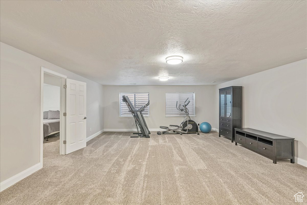 Exercise room with a textured ceiling and light carpet