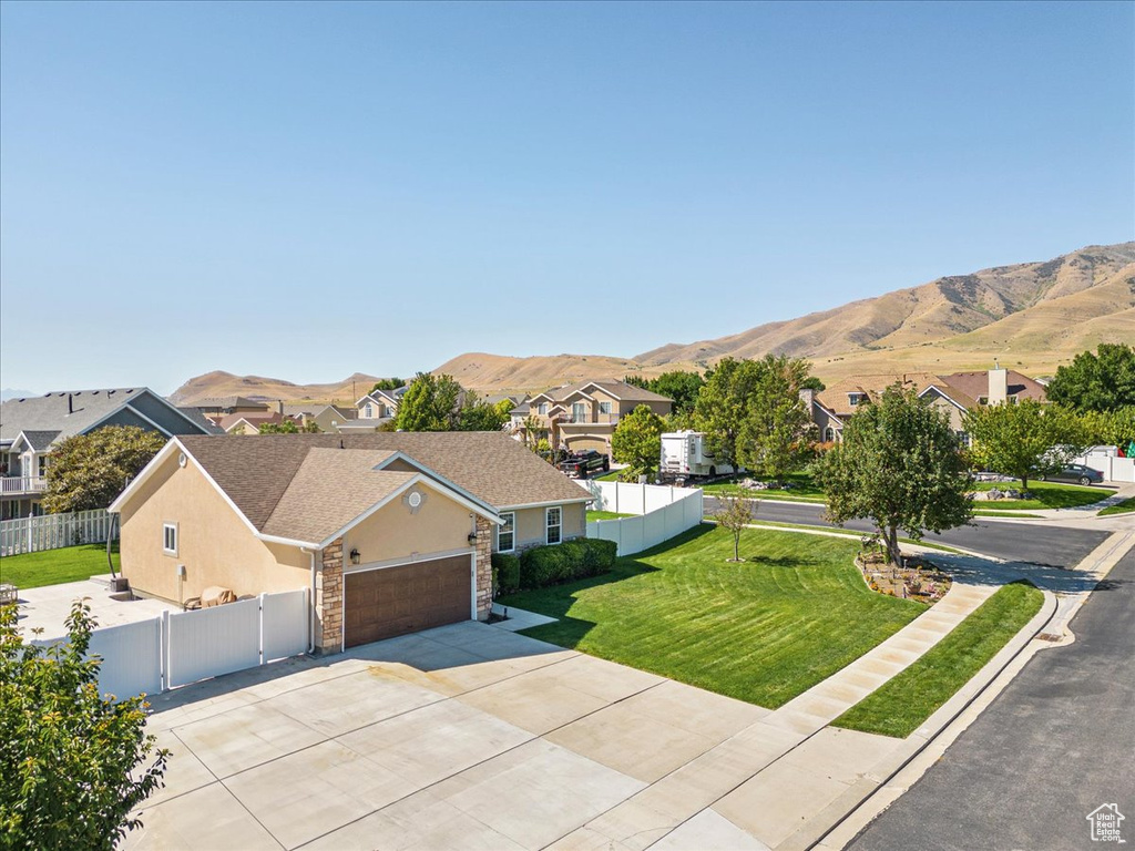 View of front of property with a garage, a front lawn, and a mountain view