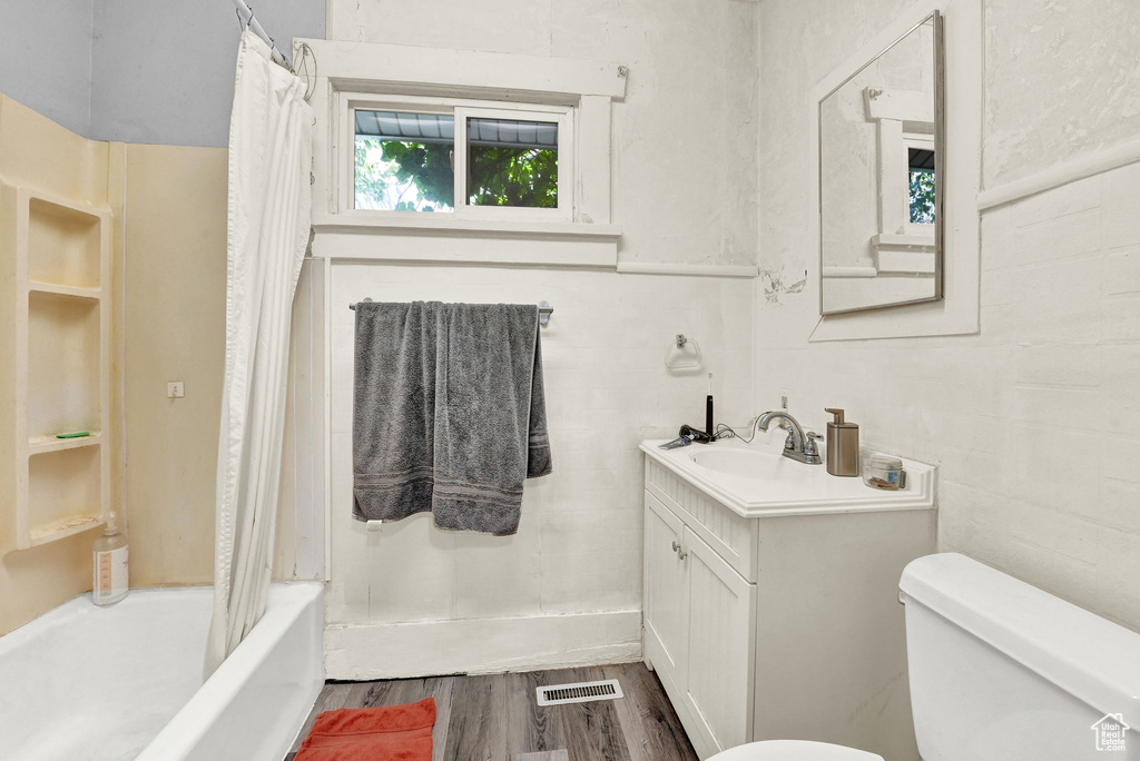 Full bathroom featuring hardwood / wood-style floors, shower / bath combo, toilet, and vanity