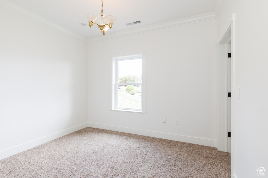 Spare room with light colored carpet, a notable chandelier, and ornamental molding