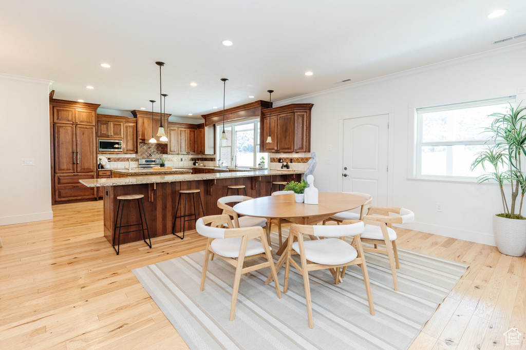 Dining room with light wood-type flooring and crown molding