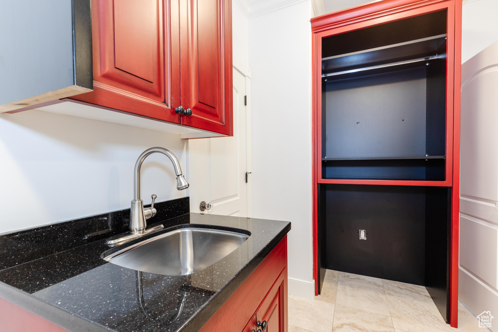 Kitchen with sink, dark stone counters, and light tile patterned flooring