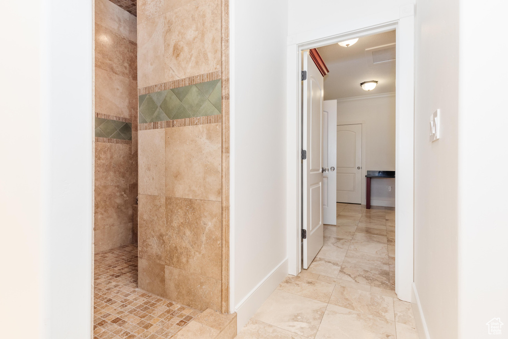 Bathroom with tile patterned floors, a tile shower, and crown molding