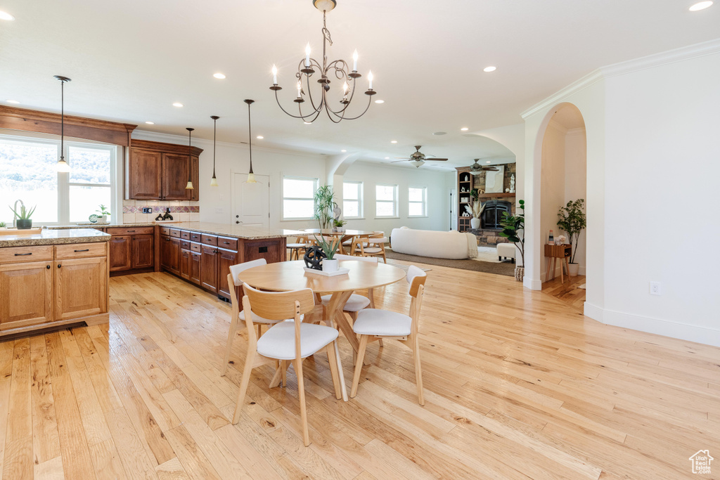 Dining area featuring light hardwood / wood-style floors, ceiling fan with notable chandelier, and ornamental molding