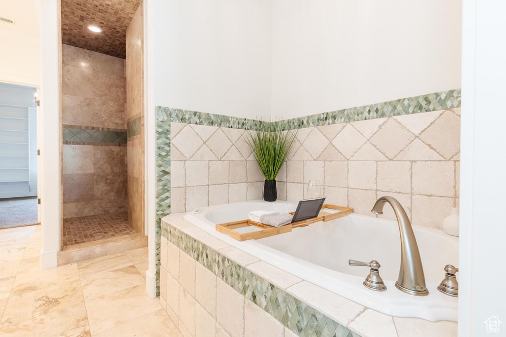 Bathroom featuring tile patterned flooring, separate shower and tub, and tile walls