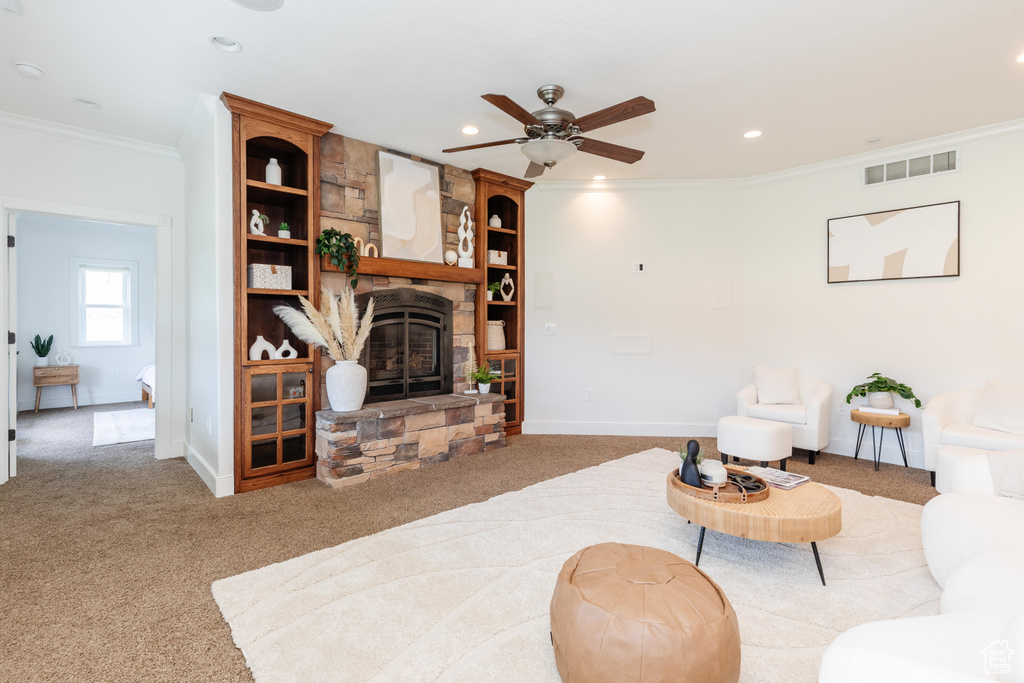 Living room featuring light colored carpet, a fireplace, crown molding, and ceiling fan