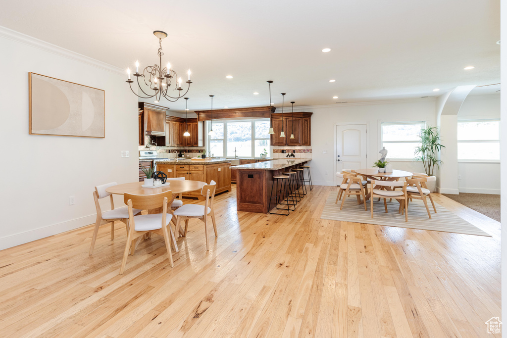 Dining room with light wood-type flooring, crown molding, and a chandelier