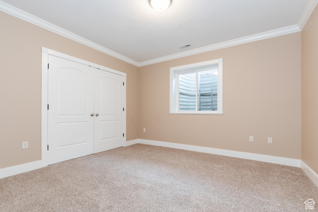 Unfurnished bedroom with carpet floors, ornamental molding, and a closet