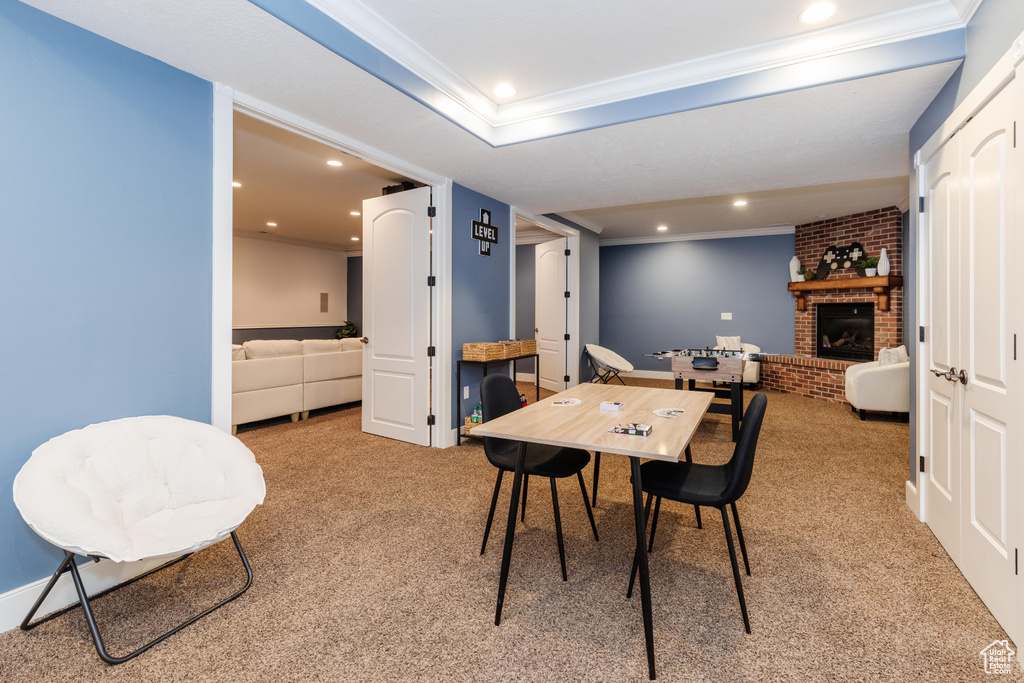 Carpeted dining space with a fireplace, brick wall, and ornamental molding