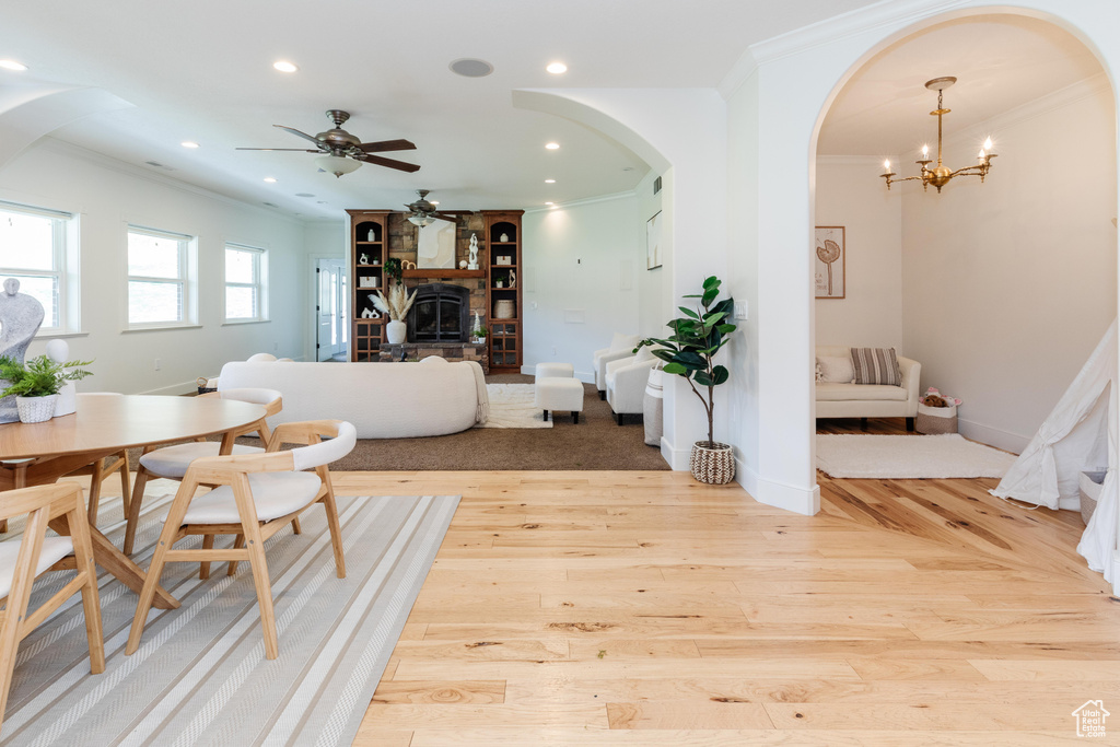 Dining area with ceiling fan with notable chandelier, light hardwood / wood-style flooring, and ornamental molding