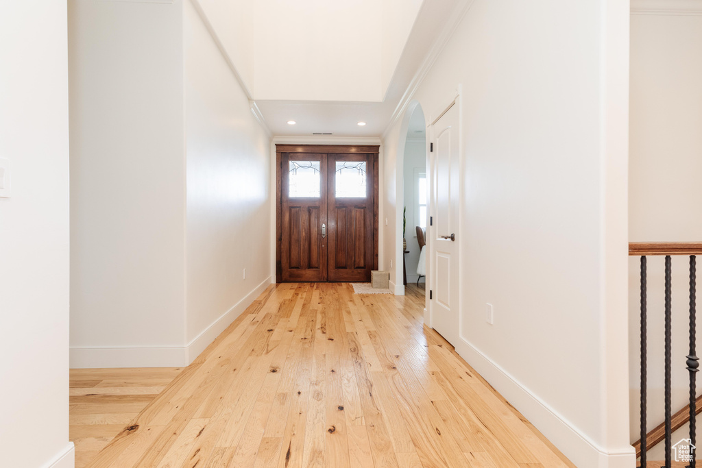 Doorway to outside with light hardwood / wood-style flooring and ornamental molding