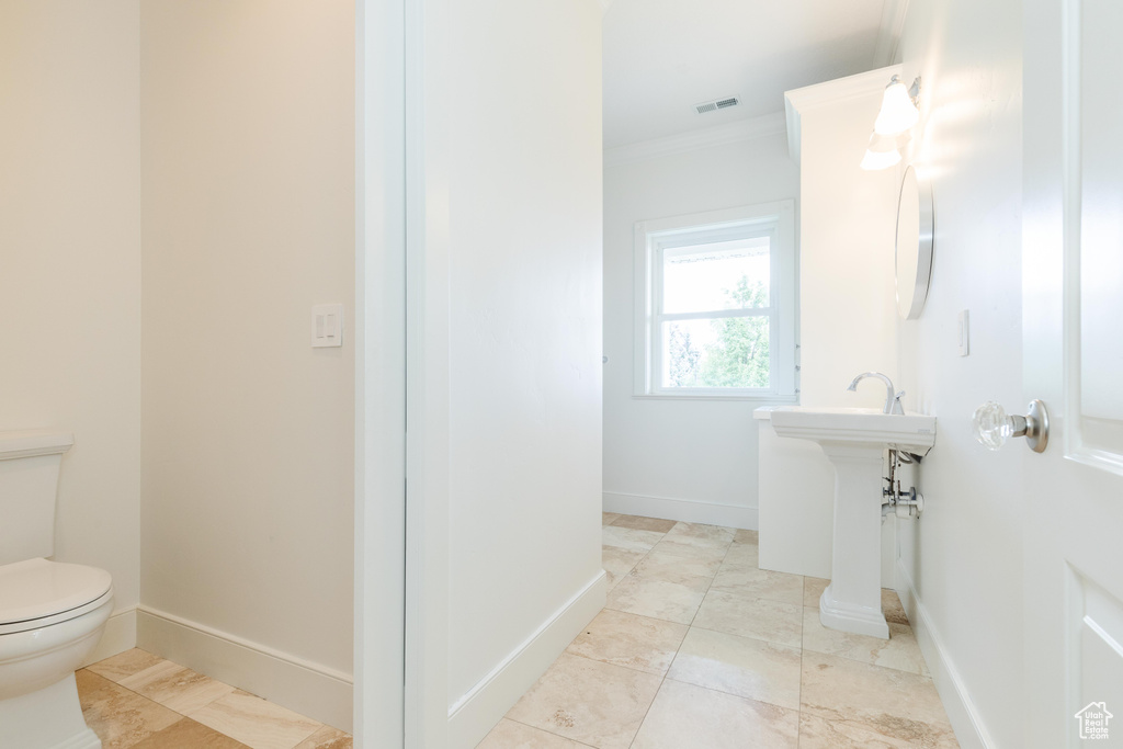 Bathroom featuring toilet, crown molding, and tile patterned floors