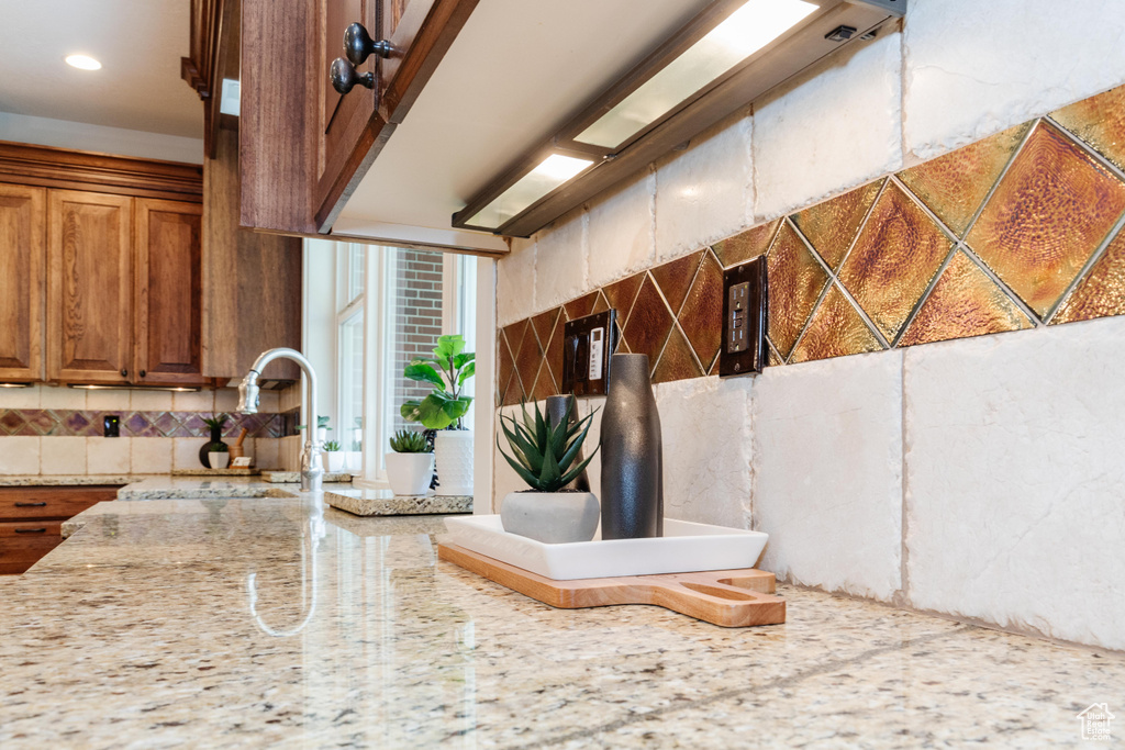 Room details with sink, light stone countertops, and tasteful backsplash