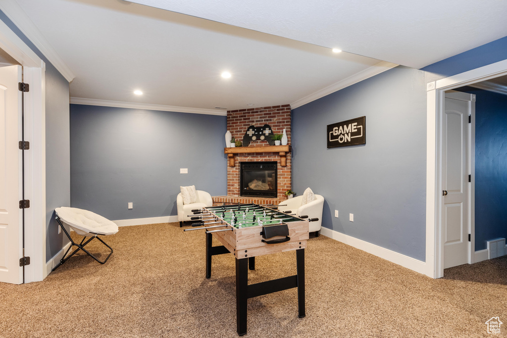 Playroom with light carpet, a fireplace, ornamental molding, and brick wall