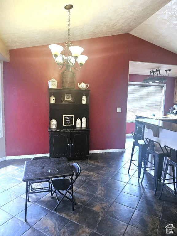 Tiled dining area featuring a notable chandelier, vaulted ceiling, and a textured ceiling