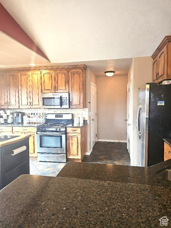 Kitchen featuring appliances with stainless steel finishes, lofted ceiling, and light tile patterned floors