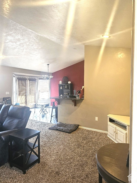 Carpeted living room featuring a notable chandelier and a textured ceiling