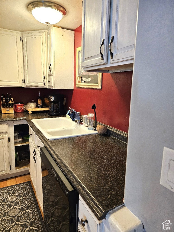 Kitchen with sink, dishwasher, white cabinetry, and light tile patterned floors