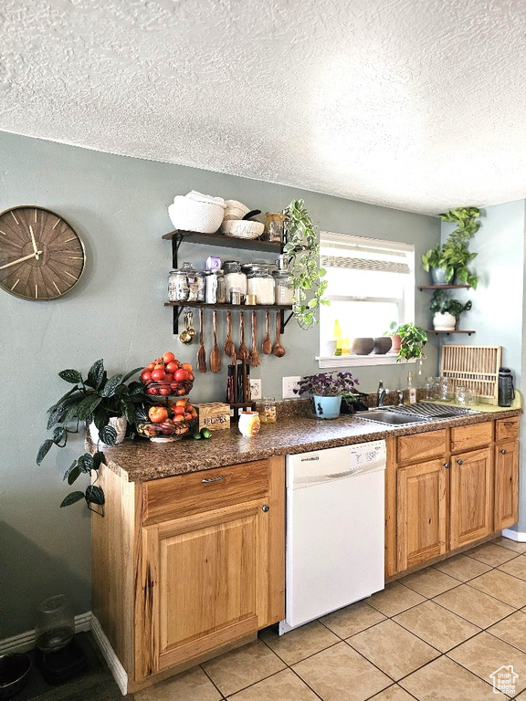 Interior space featuring a textured ceiling, light tile patterned floors, sink, and dishwasher