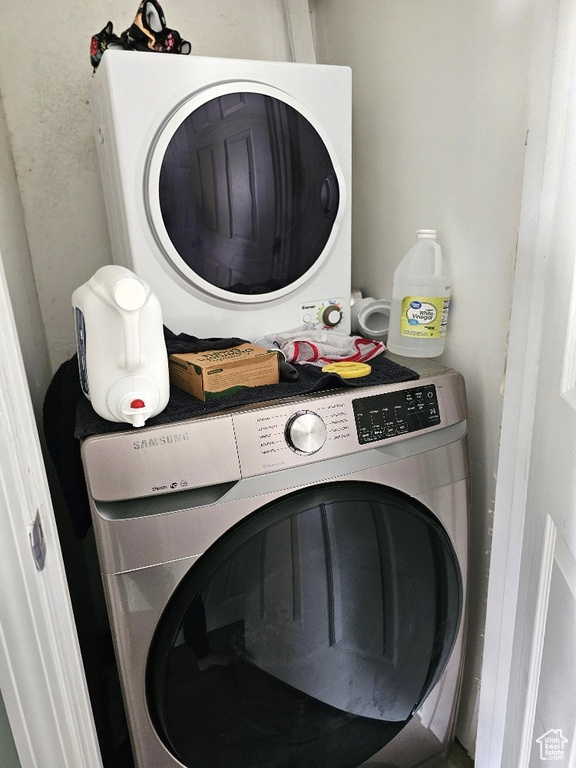 Clothes washing area featuring stacked washing maching and dryer