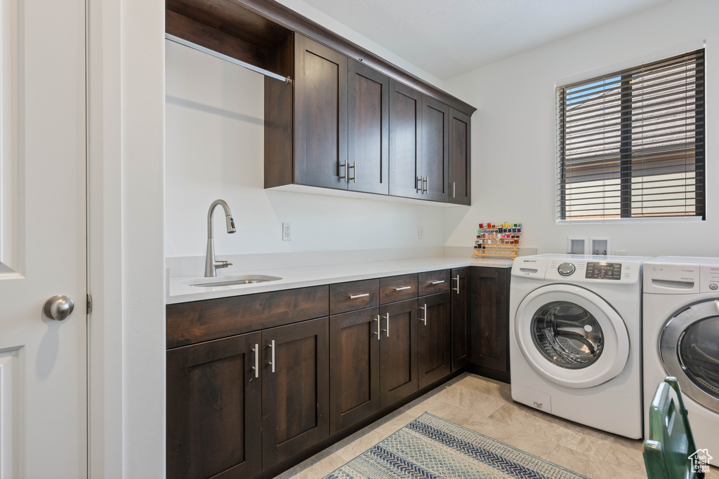 Clothes washing area featuring sink, light tile patterned floors, separate washer and dryer, and cabinets