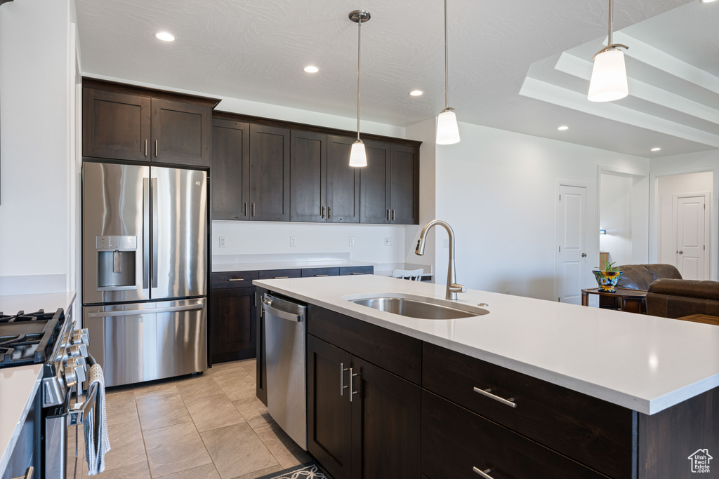 Kitchen featuring pendant lighting, light tile patterned floors, sink, stainless steel appliances, and dark brown cabinets